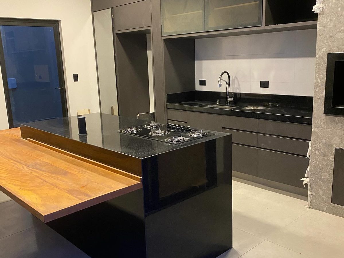 Cozinha com ilha em granito preto e prolongamento em madeira, executada a partir de projeto